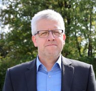 Kreisbeigeordneter Andreas Strüder steht auf einer Wiese und blickt in die Kamera.